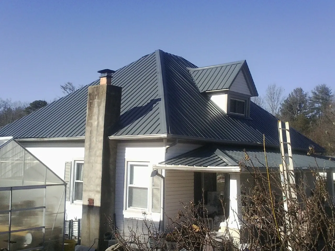 Dark blue standing seam metal roof on a white farmhouse with dormer — Slate & Tile Roof Repair by Roofing Brothers in Maine