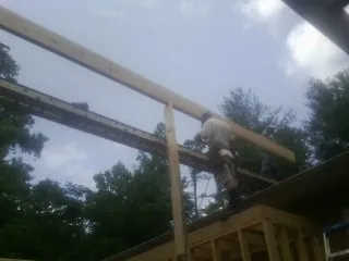 Carpenter setting a ridge beam over a new addition frame — Ice Dam Removal by Roofing Brothers in Maine