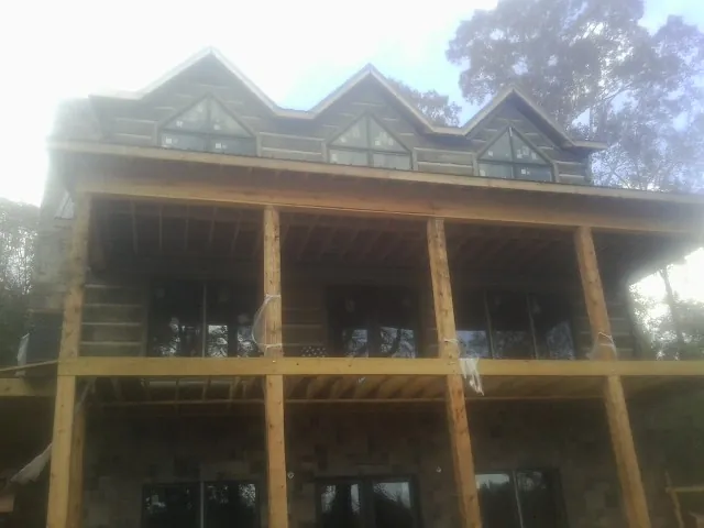 Dormers and porch framing on a large log home under construction — Roof Coating work by our crew in Maine
