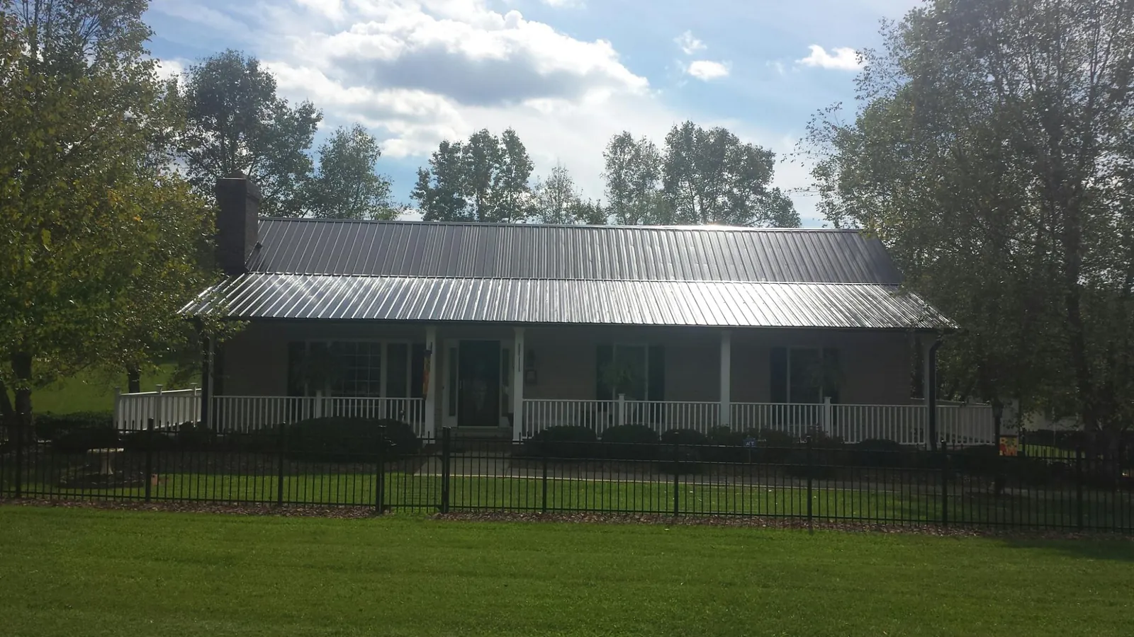 Gray metal roof on a brick ranch with a full width front porch — Gutter Guard Installation work by our crew in Maine