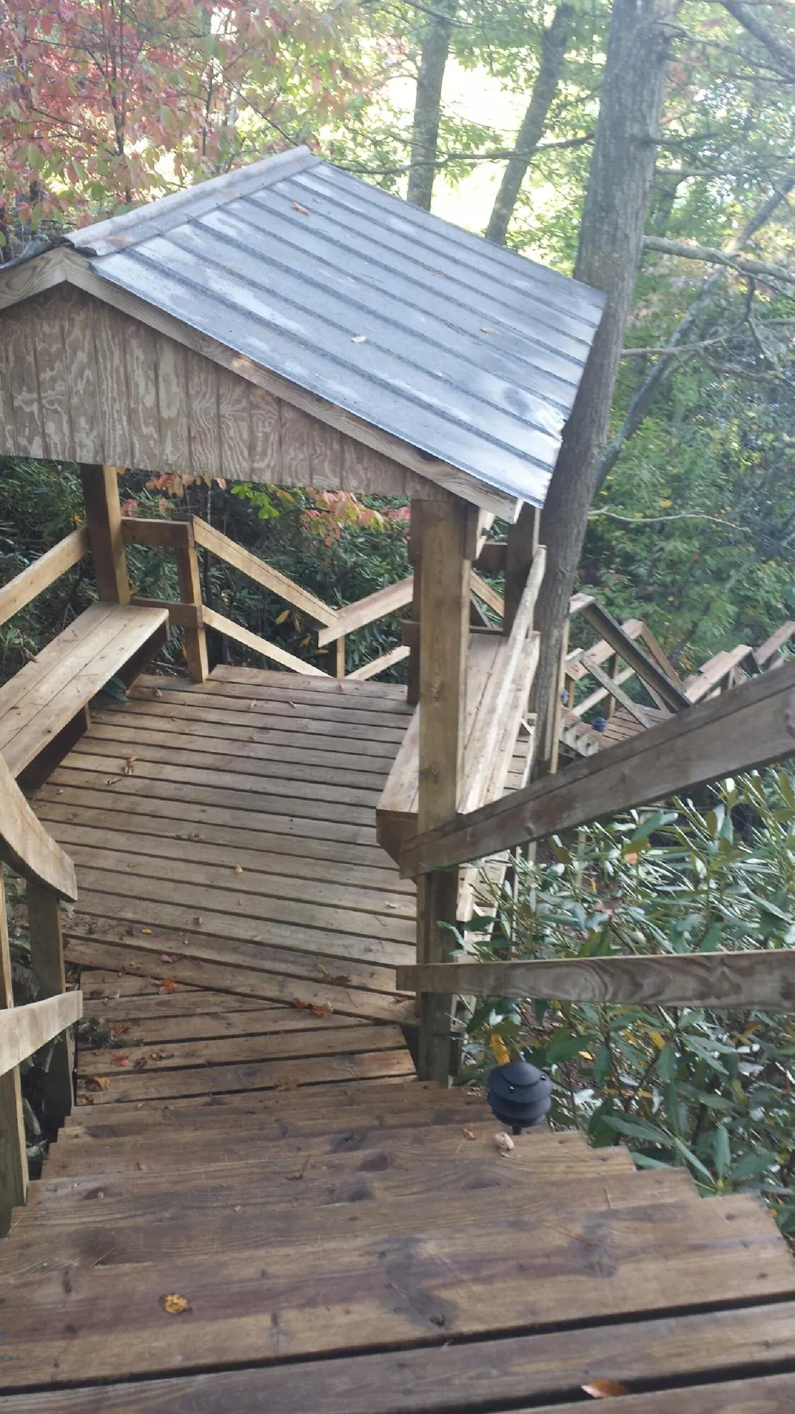 Metal roofed shelter over wooden steps on a wooded walkway — Skylight Repair & Installation work by our crew in Maine