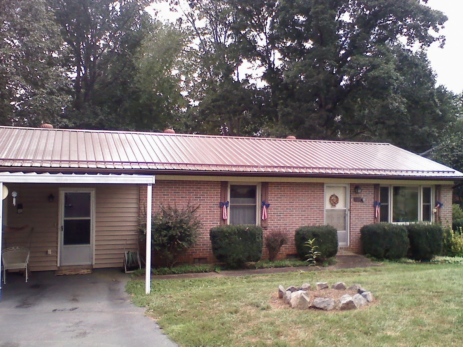 Bronze metal roof and carport on a brick ranch home — Roof Repair work by our crew in Maine